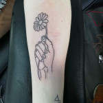Hand holding a flower tattoo