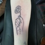 Hand holding a flower tattoo